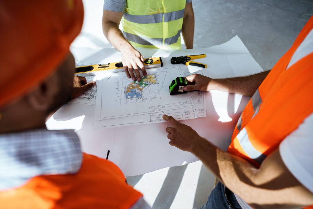 Close up of three man engineers looking at blueprint on construction site